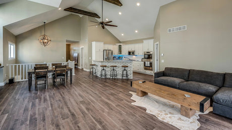 Spacious open-concept living room and kitchen with dark vinyl plank flooring.