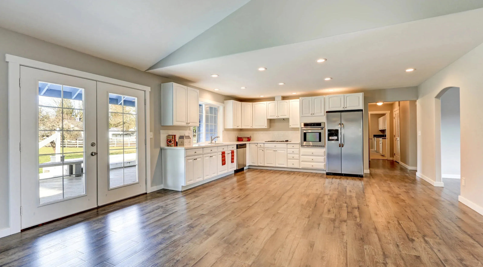Bright kitchen with white cabinets and brown laminate flooring.